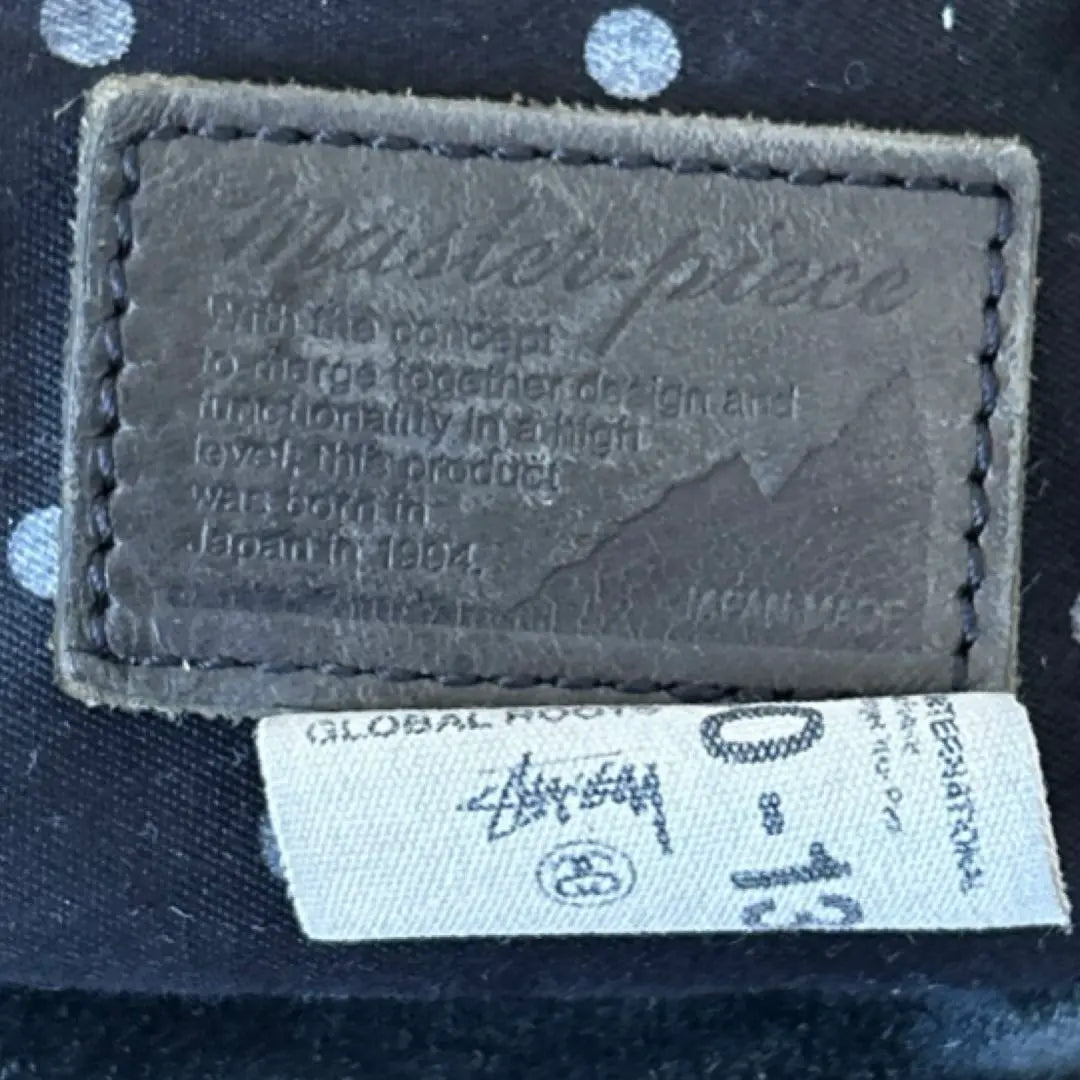 Bolso bandolera tipo sobre con diseño en colaboración entre Stussy y Masterpiece