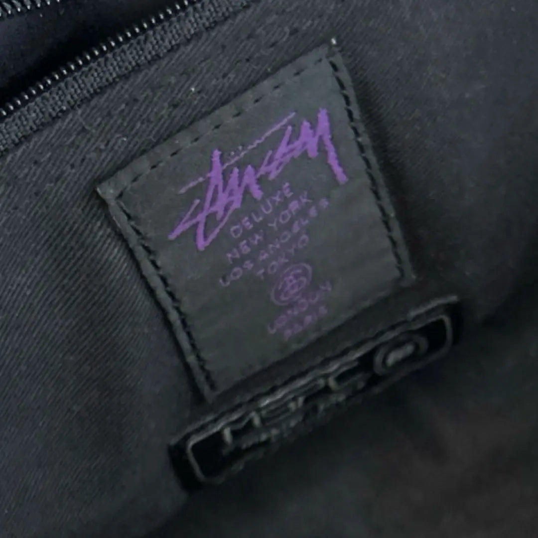 Bolso bandolera tipo sobre con diseño en colaboración entre Stussy y Masterpiece